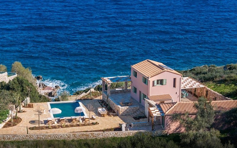 A villa and its pool terrace directly above a rocky cove